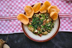 lotek is a traditional salad from Indonesia made from vegetable, chayote, kale, young jackfruit, tempeh, tofu, long beans, and bean sprouts with peanut sauce and cracker photo