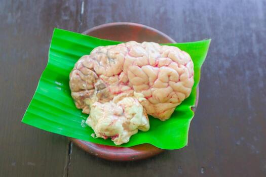 Brain cow is on a green leaf. The Brain cow is cut in half and has a red and white color photo