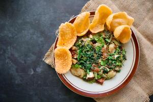 lotek is a traditional salad from Indonesia made from vegetable, chayote, kale, young jackfruit, tempeh, tofu, long beans, and bean sprouts with peanut sauce and cracker photo