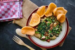 lotek is a traditional salad from Indonesia made from vegetable, chayote, kale, young jackfruit, tempeh, tofu, long beans, and bean sprouts with peanut sauce and cracker photo