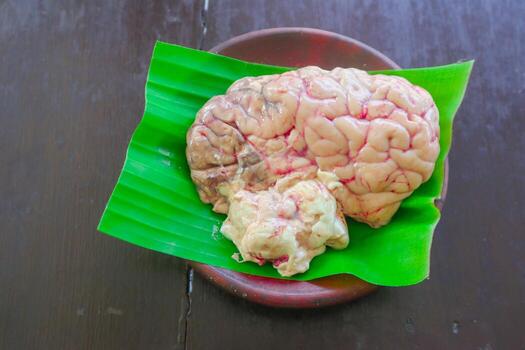 Brain cow is on a green leaf. The Brain cow is cut in half and has a red and white color photo