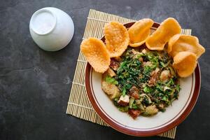 lotek is a traditional salad from Indonesia made from vegetable, chayote, kale, young jackfruit, tempeh, tofu, long beans, and bean sprouts with peanut sauce and cracker photo