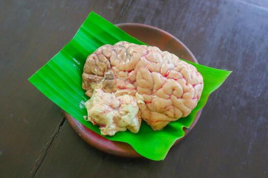 Brain cow is on a green leaf. The Brain cow is cut in half and has a red and white color photo