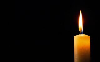 one burning candle on a black background with space for text close-up photo