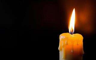 burning candle with dripping wax close-up on a black background with space for text photo