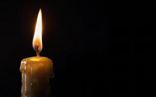burning candle and dripping wax on a black background with space for text photo