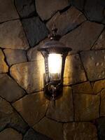 Lantern with flame in retro style on the background of a stone wall of an ancient house. photo