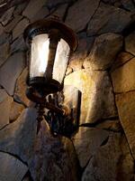 Lantern with flame in retro style on the background of a stone wall of an ancient house. photo