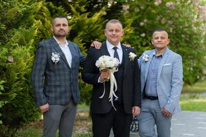 Three men are standing together, one of them holding a bouquet. They are dressed in suits and ties, and the man with the bouquet is wearing a tie as well photo