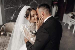 A bride and groom are hugging each other in a black suit and white veil photo