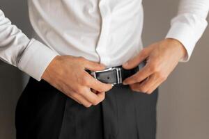 A man is adjusting his belt. Concept of formality and attention to detail photo