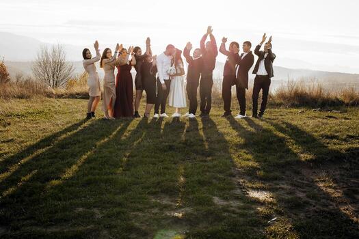 A group of people are standing in a field, with some of them wearing wedding attire. They are all smiling and holding hands, creating a sense of unity and happiness photo