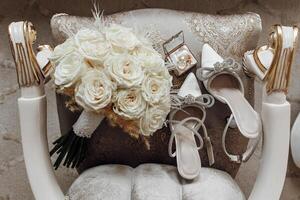 A white chair with a bouquet of white roses and a box of white shoes on it. The arrangement gives off a sense of elegance and sophistication photo
