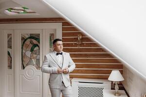 A man in a suit is standing in front of a lamp. The man is wearing a bow tie photo