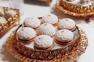 A tray of pastries with a gold frame. The pastries are small and round, and they are arranged in a circular pattern. The tray is placed on a white table photo