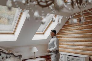A man in a suit is standing in front of a chandelier. The room has a warm and inviting atmosphere photo