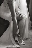 A woman in a wedding dress sits on a couch, putting on her shoes. Concept of elegance and sophistication, as the woman is dressed in a formal gown and is taking care to put on her shoes properly photo