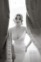 A woman in a white dress is standing in front of a curtain photo