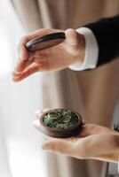 A man is holding a wooden box with two rings inside. The box is green and has a mossy texture. The man is wearing a suit and tie. Concept of elegance and sophistication photo