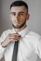 A man in a white shirt and black tie is posing for a photo. The image has a blurred effect, giving it a dreamy or artistic feel. The man's facial expression photo