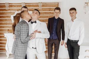 A group of men are dressed in suits and ties, with one man kissing another. Scene is playful and lighthearted, as the men are dressed up and engaging in a fun activity photo