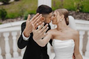 A bride and groom are kissing each other's hands, with the bride wearing a white dress. Concept of love and commitment, as the couple shares a tender moment together photo