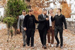 A group of men are walking down a street in suits and ties. They are smiling and seem to be enjoying each other's company photo