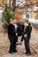 A group of men are posing for a picture, with one man holding another man up. Scene is lighthearted and fun, as the men are enjoying themselves and posing for the camera photo
