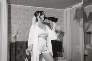 A woman in a white gown is drinking from a bottle of wine photo