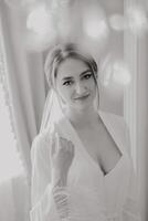 A woman is wearing a white robe and is smiling. She is posing for a picture. The photo is in black and white