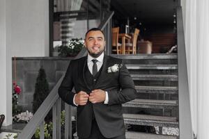 A man in a suit and tie stands on a staircase. He is smiling and he is getting ready for a special occasion photo
