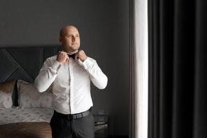 A man in a suit is getting ready to tie his bow tie. Concept of formality and preparation for a special occasion photo