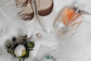 A pair of white shoes and a bottle of perfume are on a white surface photo