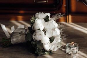 A bouquet of white flowers sits on a wooden table next to a small box. The flowers are arranged in a way that they look like they are about to be arranged in a vase photo