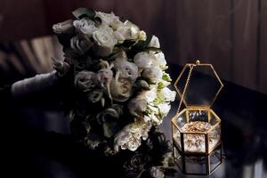 A bouquet of white flowers sits next to a gold box photo
