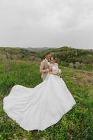 A bride and groom are standing in a field photo