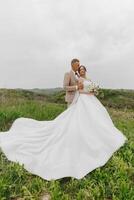 A bride and groom are standing in a field photo