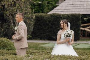 A bride and groom are standing in a garden, the bride holding a bouquet photo