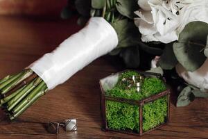A bouquet of white flowers sits on a table next to a small box with a green moss inside photo