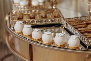 A table with a variety of desserts, including cakes and cookies, arranged in a circular pattern. The desserts are displayed on a gold tray, and there are several different types of cakes and cookies photo