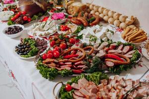 A table is covered with a variety of meats, vegetables, and bread photo