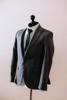 A man is wearing a black tie and a gray jacket. The jacket has a pattern of snakes on it photo