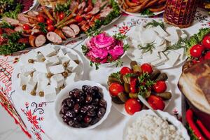 A table is covered with a variety of foods, including cheese, olives, tomatoes photo