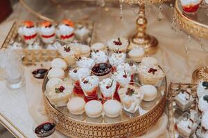 A table with a variety of desserts, including cakes, pastries, and fruit tarts. The desserts are arranged in small, individual serving dishes, and there are also some drinks on the table photo