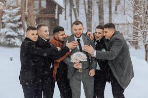 A group of men are posing for a picture in the snow, with one man holding a bouquet of flowers. Scene is festive and joyful, as the men are dressed up and smiling for the camera photo