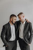 Two men in suits are smiling and hugging each other. Scene is happy and friendly photo