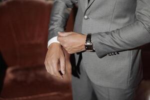 A man in a suit is adjusting his watch. Concept of formality and attention to detail photo