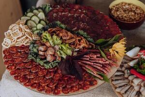 A large platter of assorted meats and vegetables is displayed on a table. The platter is filled with a variety of meats, including sausage, ham, and salami, as well as vegetables such as lettuce photo