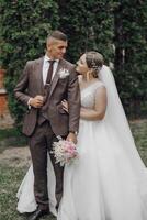 A bride and groom are standing in a grassy area photo