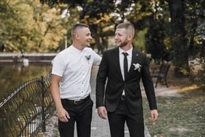 Two men in suits are walking together in a park photo